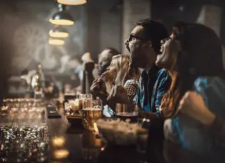 8 Places to Watch the Big Game in McAllen! Group of cheerful fans cheering for their team in a bar.