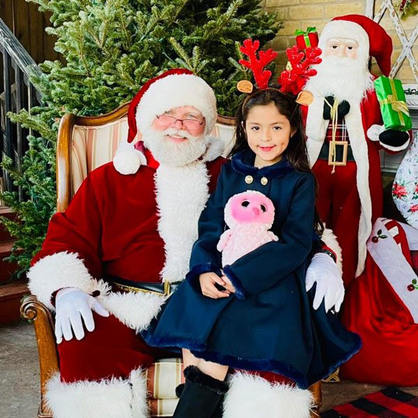 Santa sitting with a girl in blue at the mcallen clothing store