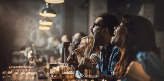 Group of cheerful fans cheering for their team in a bar.