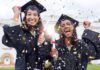 Two young women in McAllen are smiling, dressed in black graduation gowns while confetti falls all over them.