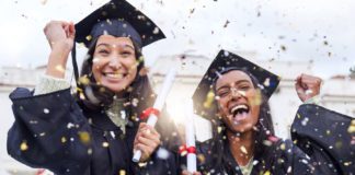 Two young women in McAllen are smiling, dressed in black graduation gowns while confetti falls all over them.