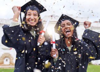 Two young women in McAllen are smiling, dressed in black graduation gowns while confetti falls all over them.