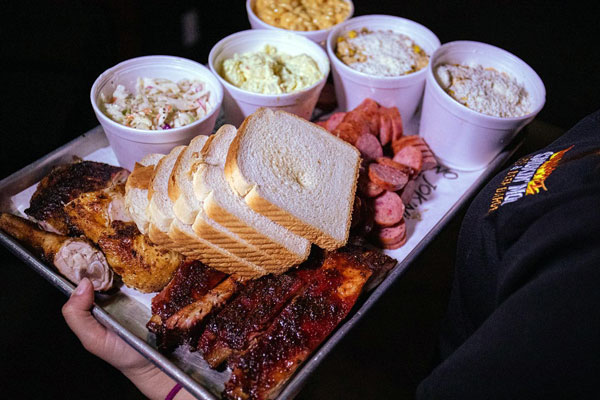A full plate of brisket and side dishes, such as mac and cheese, coleslaw, sausage, and bread are served from one of the popular McAllen restaurants.